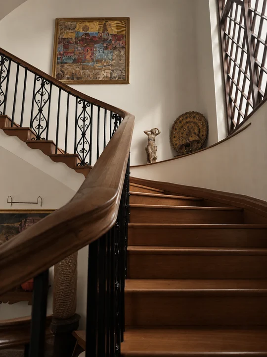 A curved stair with a hardwood handrail, iron balustrade and tall timber window