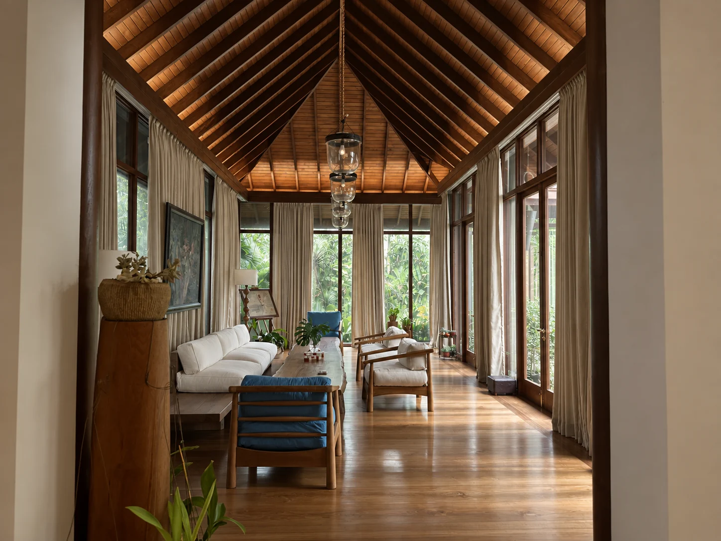 A light-filled interior with hardwood furniture, tall windows and an exposed timber ceiling